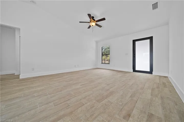 Spare room featuring lofted ceiling, light wood-type flooring, and a ceiling fan
