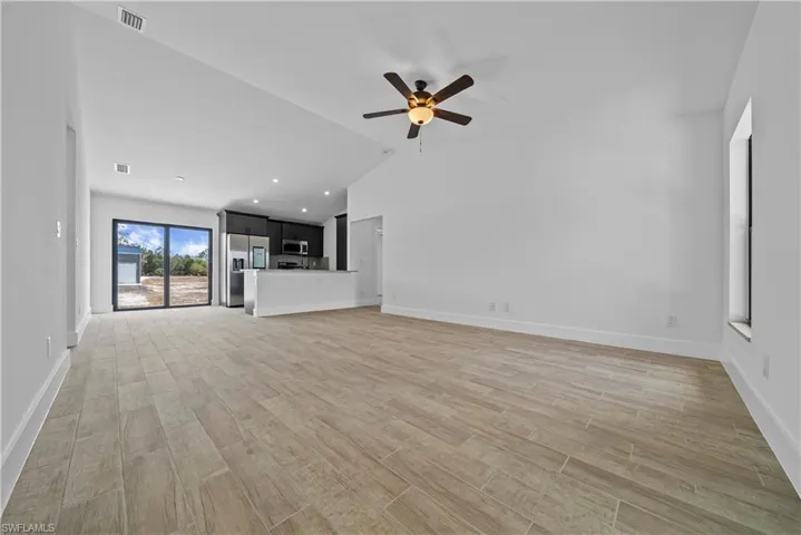Unfurnished living room featuring wood tiled floors, ceiling fan, lofted ceiling, and recessed lighting