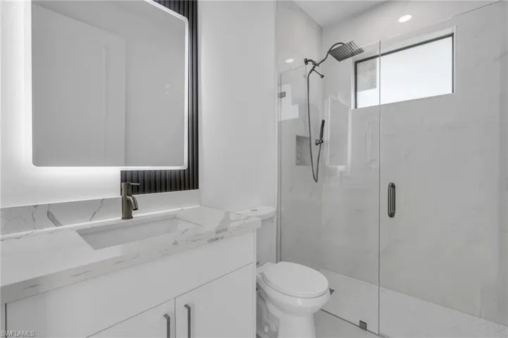 Bathroom featuring vanity, toilet, and a shower with door