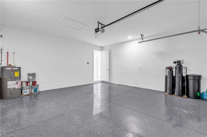 Garage featuring electric water heater and a garage door opener