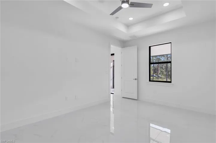 Empty room featuring ceiling fan and a tray ceiling