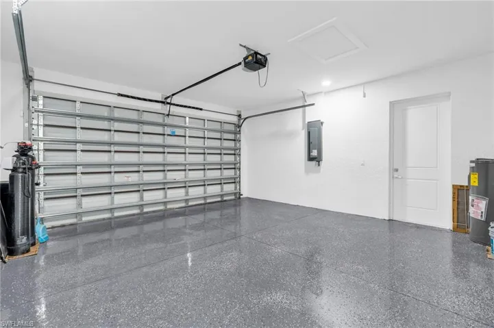 Garage featuring water heater, electric panel, and a garage door opener