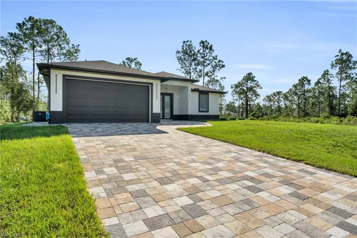 View of front of house with a garage, a front lawn, and central air condition unit