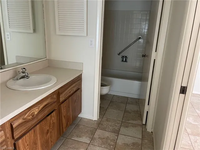 Full bathroom with tile patterned flooring, tiled shower / bath combo, toilet, and vanity