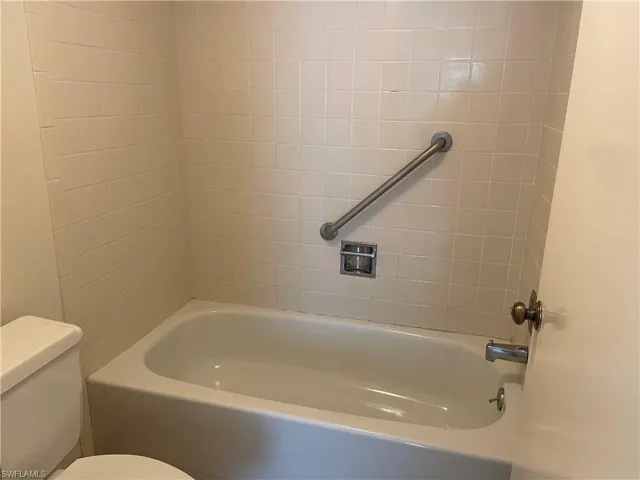 Bathroom with tiled shower / bath combo and toilet