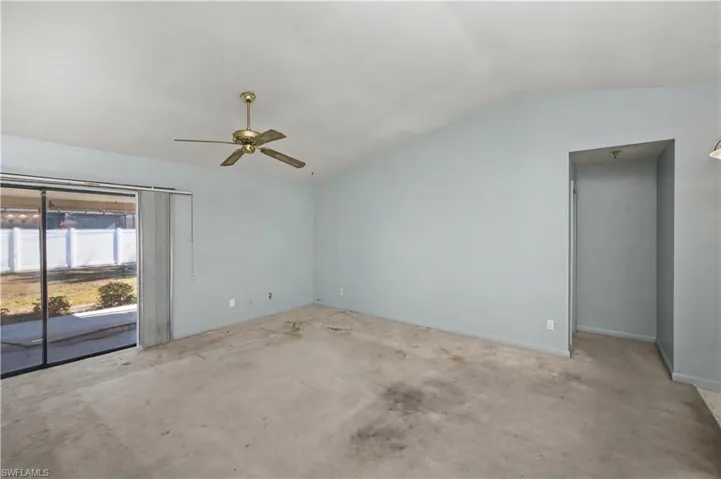 Spare room with vaulted ceiling, ceiling fan, and unfinished concrete flooring