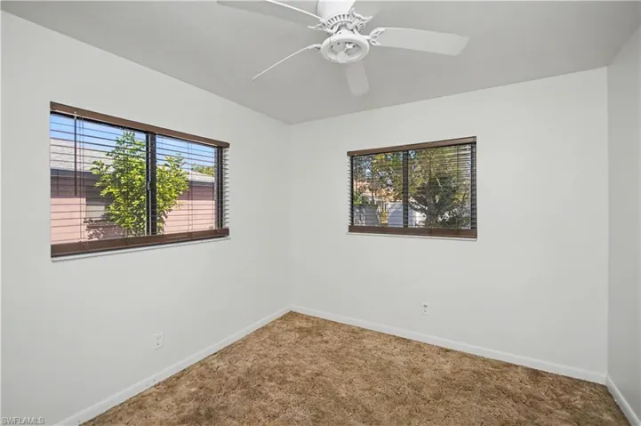 Carpeted spare room featuring baseboards and a ceiling fan