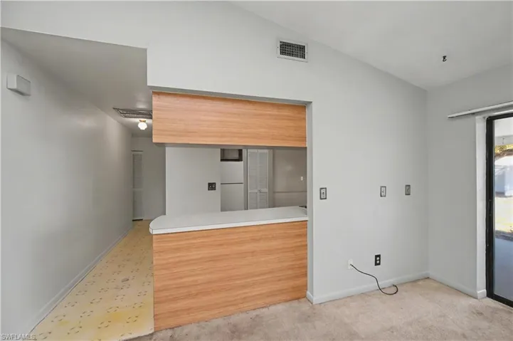 Kitchen with lofted ceiling, light countertops, freestanding refrigerator, and light carpet