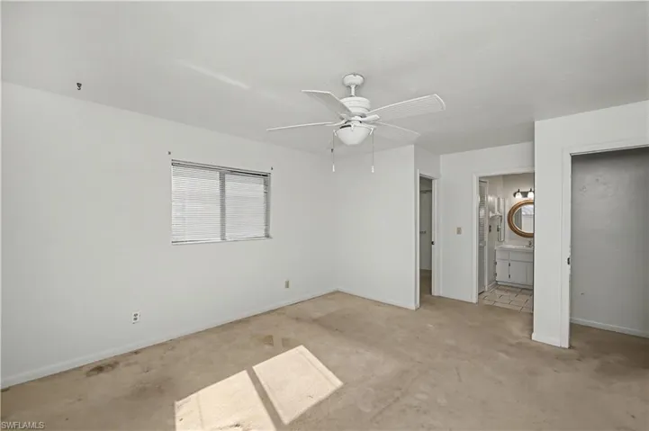 Unfurnished bedroom with a walk in closet, ceiling fan, carpet, and connected bathroom