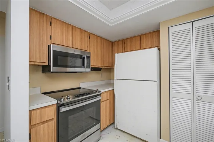 Kitchen with stainless steel appliances, light countertops, and brown cabinets