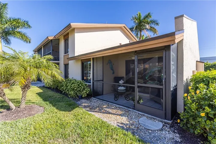 Rear view of property with a sunroom, a lawn, and stucco siding