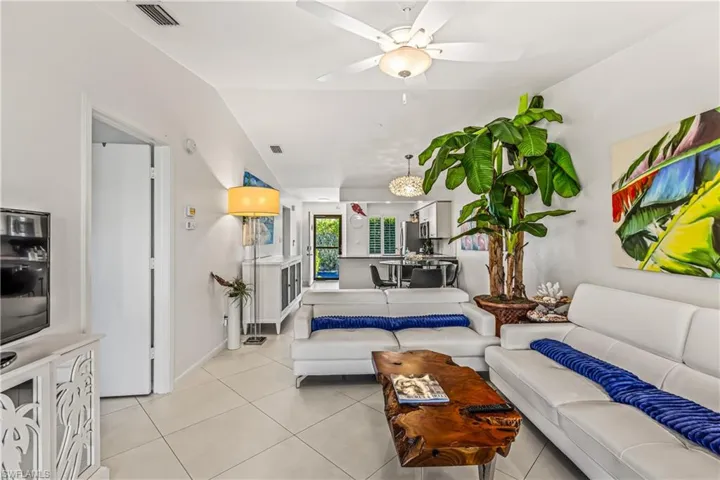 Living room featuring a ceiling fan, light tile patterned flooring, and vaulted ceiling