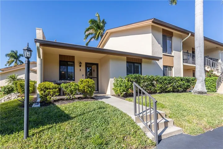 View of front of house with a front yard, stucco siding, and covered porch