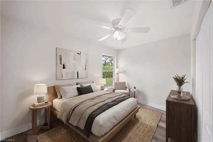 Neutral-toned interior featuring wood-finish flooring, a central ceiling fan with integrated light fixture, a single-hung window, and a reach-in closet with double doors