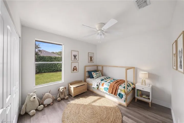 Neutral-toned room featuring wood-finish flooring, a single-hung window, and a white ceiling fan with integrated lighting
