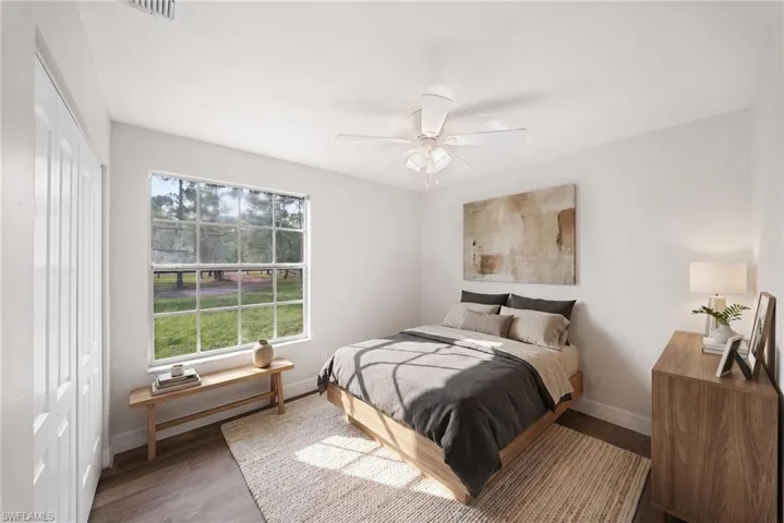 Room featuring wood-finish flooring, a multi-pane window, and an integrated ceiling fan with light fixture