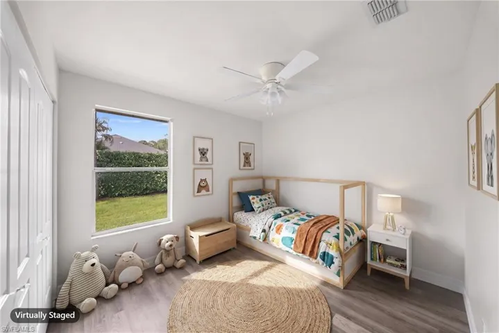 Neutral-toned wood-finish flooring, single-hung window with exterior greenery, and white ceiling fan with integrated light fixture