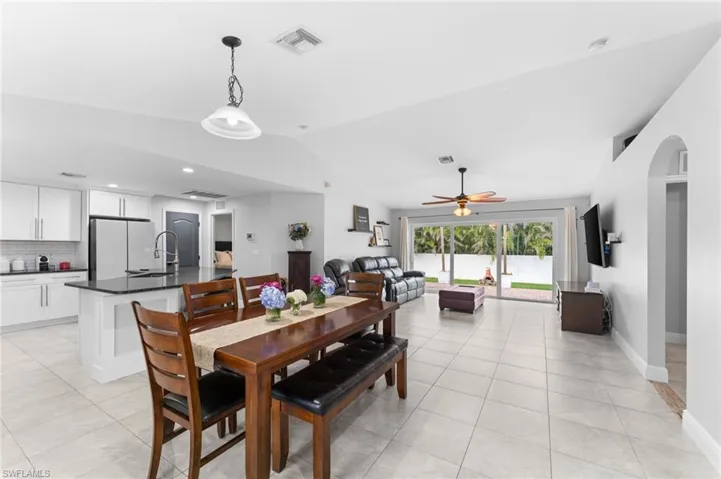 Tiled dining area with sink, vaulted ceiling, and ceiling fan