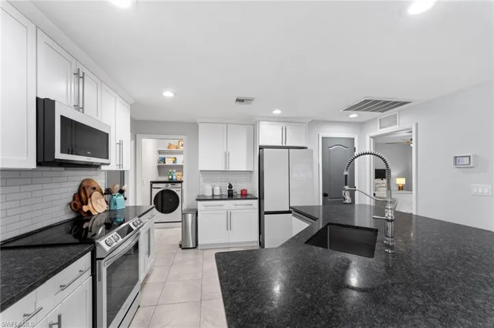 Kitchen featuring electric stove, white cabinets, white fridge, and washer / clothes dryer