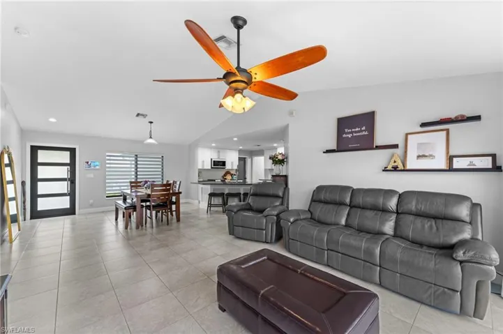 Living room featuring ceiling fan, light tile patterned floors, and vaulted ceiling
