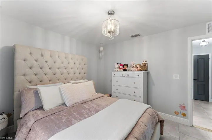 Bedroom with light tile patterned floors and an inviting chandelier
