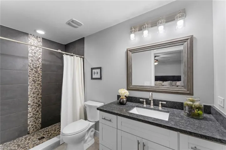 Bathroom with vanity, toilet, curtained shower, and tile patterned floors
