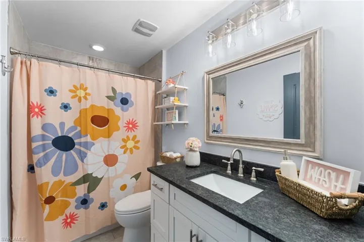 Bathroom with tile patterned floors, toilet, vanity, and a shower with curtain