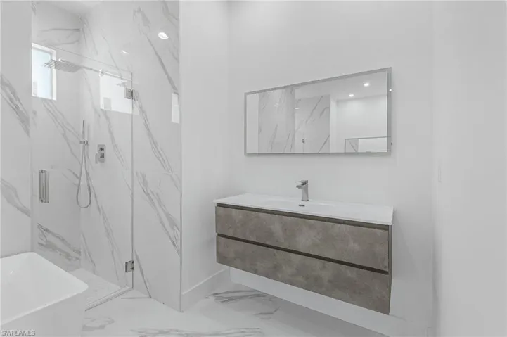 Full bath with marble finish floors, a marble finish shower, a freestanding tub, and vanity