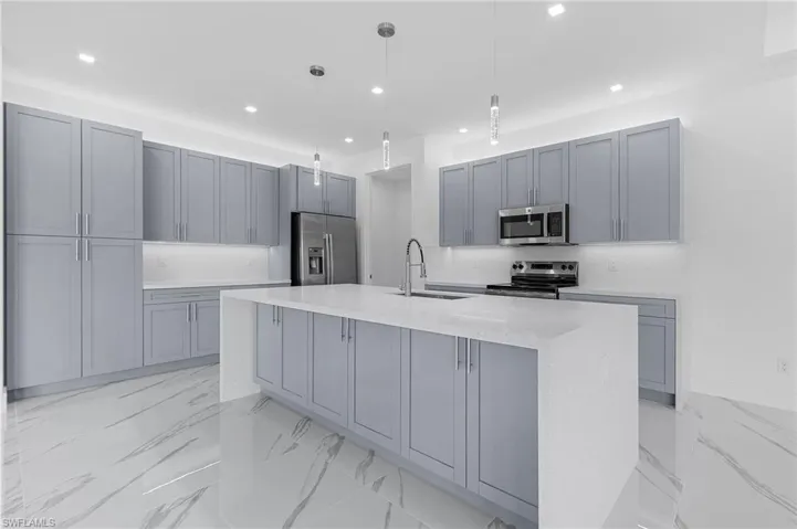 Kitchen with gray cabinetry, light marble finish floors, light stone countertops, and recessed lighting