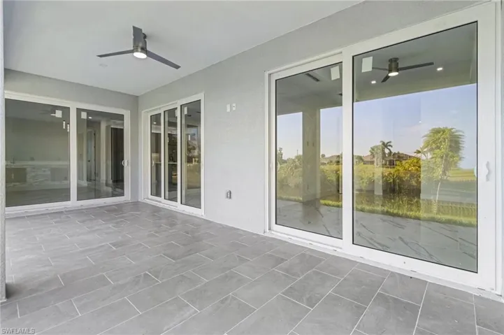 Unfurnished sunroom with ceiling fan and a patio area