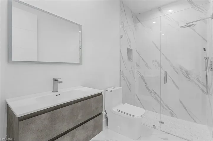 Full bathroom featuring vanity, a marble finish shower, and marble finish flooring