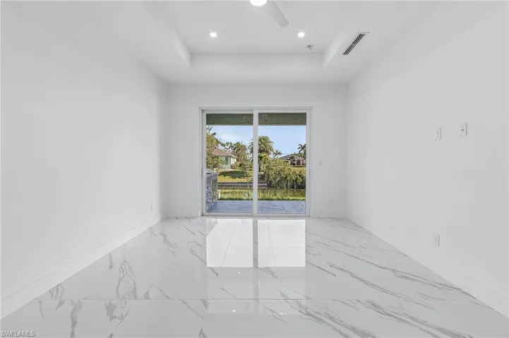 Empty room featuring marble tiled floors, a tray ceiling, recessed lighting, and ceiling fan