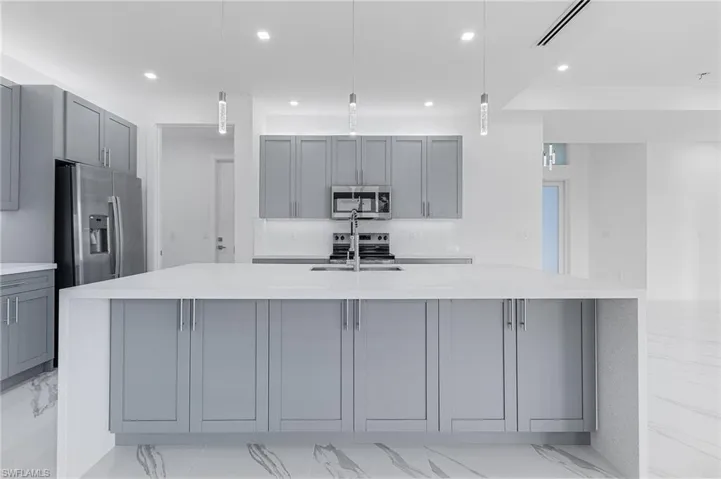 Kitchen featuring gray cabinetry, light marble finish floors, light stone counters, hanging light fixtures, and recessed lighting