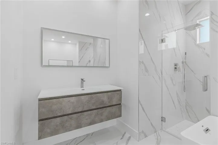 Bathroom featuring a marble finish shower, marble finish flooring, vanity, and a tub to relax in