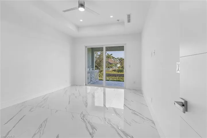 Spare room featuring marble finish floors, a raised ceiling, recessed lighting, and ceiling fan