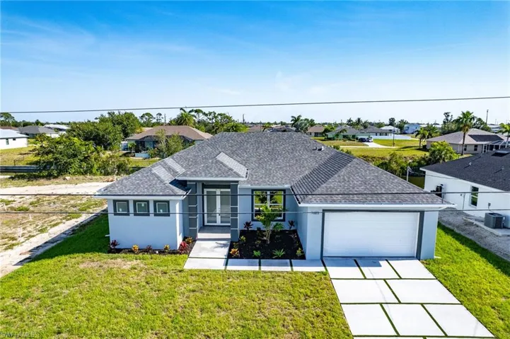 View of front of house with stucco siding, driveway, a front yard, a shingled roof, and a residential view