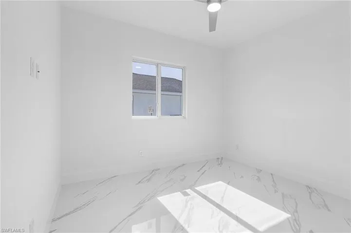 Spare room featuring marble finish flooring and a ceiling fan