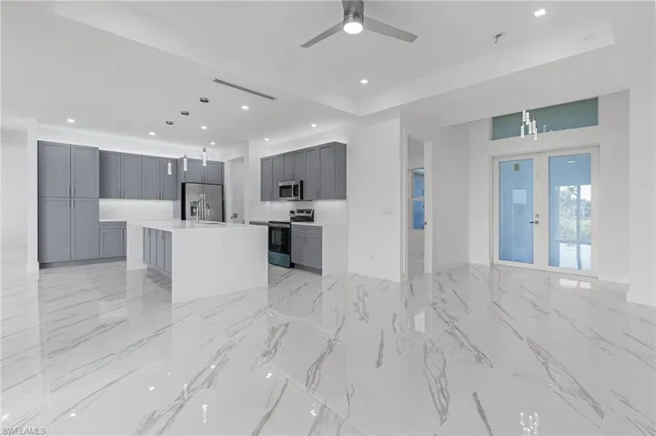 Unfurnished living room with recessed lighting, light marble finish floors, french doors, and ceiling fan