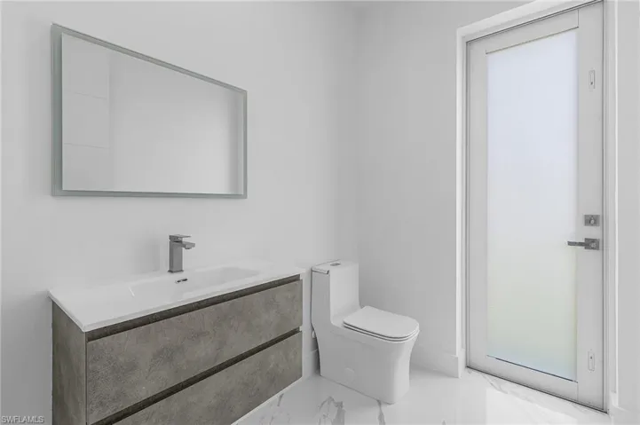 Half bath with marble finish floors and vanity
