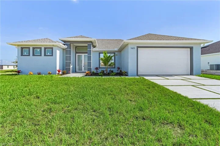 View of front of property featuring stucco siding, a front lawn, driveway, and an attached garage