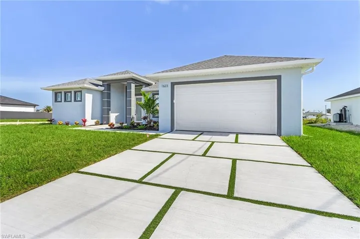 View of front of home featuring a front yard, stucco siding, a garage, and driveway