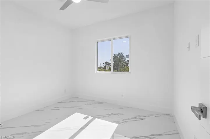 Spare room with marble look tile flooring and ceiling fan