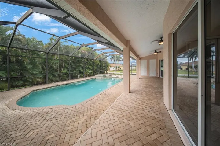 View of swimming pool with a patio, glass enclosure, a sunroom, and a pool with connected hot tub
