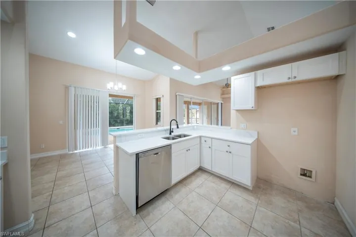 Kitchen featuring white cabinetry, a peninsula, recessed lighting, stainless steel dishwasher, and a chandelier