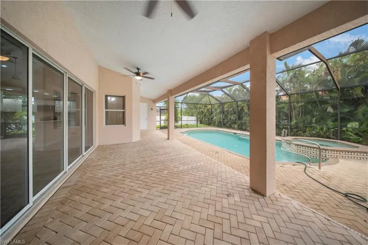 View of pool featuring a patio area, a ceiling fan, a sunroom, glass enclosure, and a pool with connected hot tub