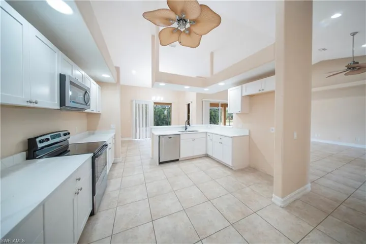 Kitchen featuring stainless steel appliances, recessed lighting, white cabinets, ceiling fan, and a peninsula