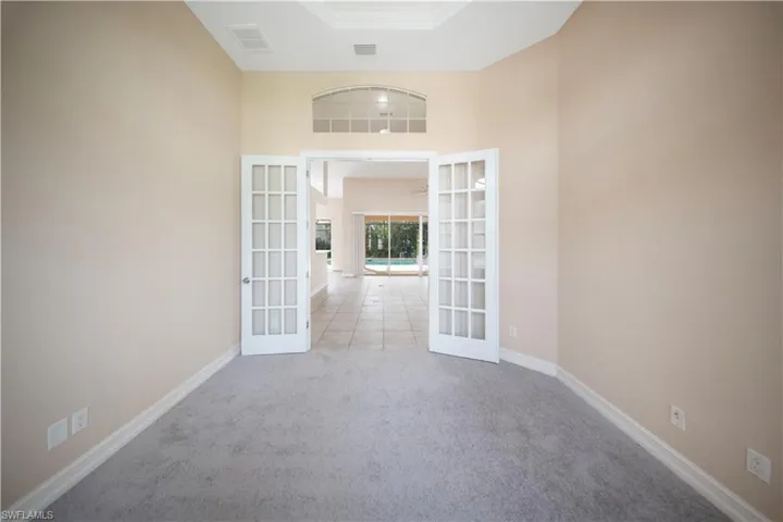 Unfurnished room featuring french doors, carpet floors, and a towering ceiling
