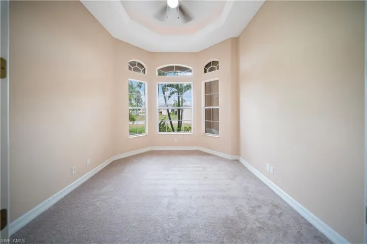 Carpeted spare room with a tray ceiling and ceiling fan