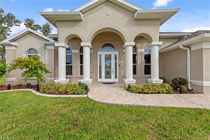 Doorway to property with stucco siding, covered porch, and a lawn