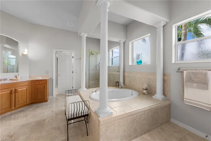 Full bath featuring vanity, a stall shower, a garden tub, and light tile patterned floors